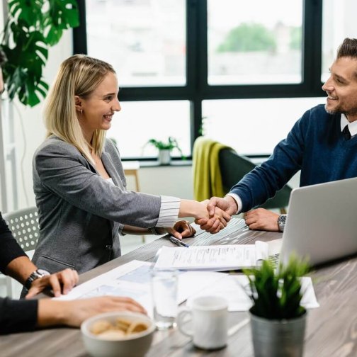 Imagen ilustrativa del servicio de Outsourcing: Ejecutivos de dos empresas distintas estrechando la mano en señal de acuerdo.